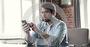 Young man holding smartphone feels angry due problem with gadget