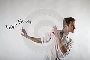 Young man holding smartphone in his hands. Antipathy, dislike and refuse concept. Fake news photo