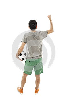 Young man holding soccer ball in hand looking at wall. Rear view