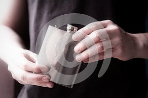 Young man holding a stainless steele Hip Flask with liquor, alcohol and booze concept