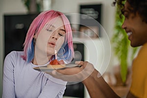 Young man holding a straberry cake with a candle, his girlgriend happy