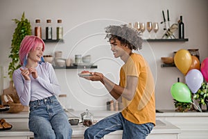 Young man holding a straberry cake with a candle, his girlgriend happy