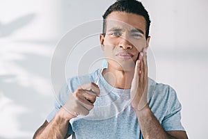 Young man holding toothbrush while having toothpain