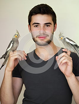 Young man holding two parrots