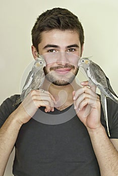 Young man holding two parrots