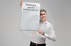 Young man holding a vehicle sales agreement isolated on a light background