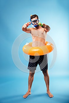 Young man holding water guns and swimmng circle