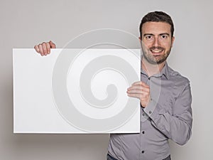 Young man holding a white copyspace billboard