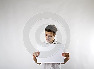 Young man holding white paper in his hands. Crazy.