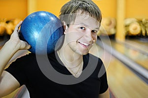 Young man holds ball in bowling club