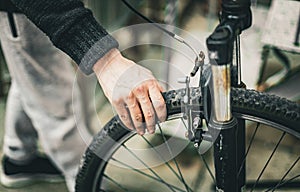 A young man holds a bicycle wheel with his hand.