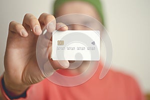 A young man holds a blank bank credit card. Cashless payments, banks, loans and online payment concept