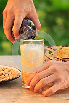 Young man holds bottle of beer and fills glass