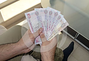 Young man holds in hands dirhams paper money.