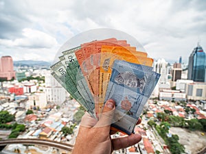 A young man holds in his hands the money of Malaysia against the background of the city center of Kuala Lumpur. photo