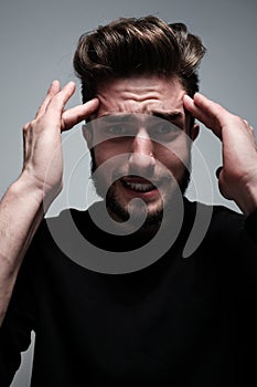 A young man holds his head and shows different human emotions: hatred, fear, despair, horror, malaise, headache, clairvoyance.