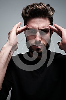 A young man holds his head and shows different human emotions: hatred, fear, despair, horror, malaise, headache, clairvoyance.