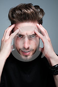 A young man holds his head and shows different human emotions: hatred, fear, despair, horror, malaise, headache, clairvoyance. photo