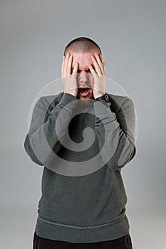 Young man holds his head on a white background. emotions