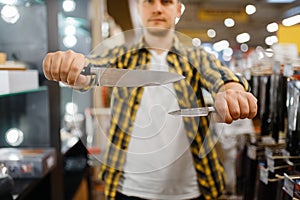 Young man holds kitchen knives in houseware store