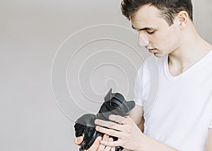 A young man holds a photo camera and looks at it. Isolated gray background photo