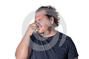 A young man holds or pinches his nose shut because of a stinky smell or odor