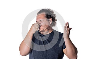 A young man holds or pinches his nose shut because of a stinky smell or odor. Isolated on a white background