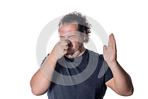 A young man holds or pinches his nose shut because of a stinky smell or odor. Isolated on a white background photo
