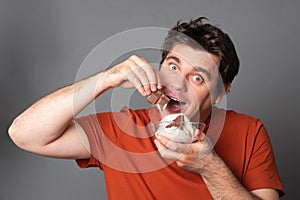 Young man holds a plate of chocolate ice cream. Fanny man with an appetite eats ice cream