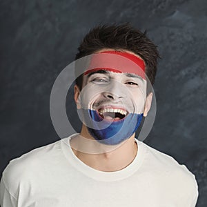 Young man with Holland flag painted on his face