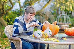 Young man hollowing out a pumpkin to prepare halloween lantern