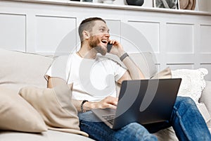 young man at home on the couch talking on the phone, side view