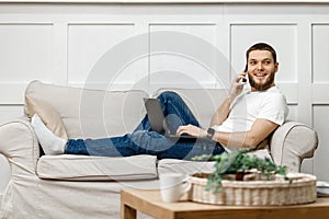 young man at home on the couch talking on the phone, side view