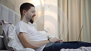 young man at home on the couch talking by video with a laptop