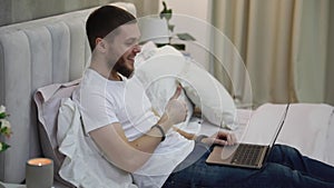 young man at home on the couch talking by video with a laptop