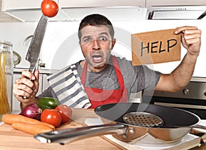 Young man at home kitchen in cook apron desperate in cooking stress