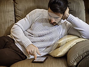 Young man at home reading with ebook reader