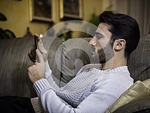 Young man at home reading with ebook reader