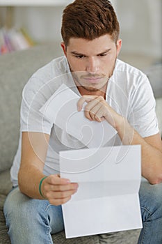 Young man at home reading letter