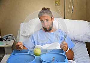 Young man in hospital room after suffering accident eating healthy apple diet clinic food moody and sad