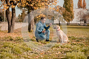 Young man hugging golden retriever dog in autumn outdoors