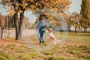 Young man hugging golden retriever dog in autumn outdoors