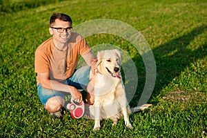 Young man hugging golden retriever dog in summer outdoors