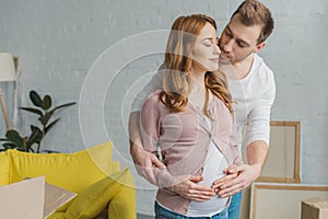 young man hugging and kissing happy pregnant woman