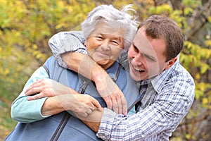 Young man hugs elderly woman