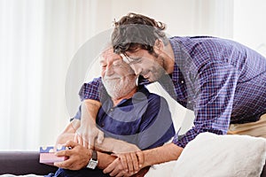 Young man hugs the uncle old man warmly inside the house, son happy and love his father or grand father with gift box concept