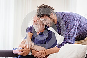 Young man hugs the uncle old man warmly inside the house, son happy and love his father or grand father with gift box concept photo