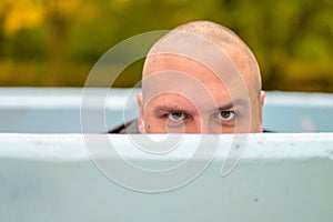 Young man hunkering down in an outdoor tub or pool