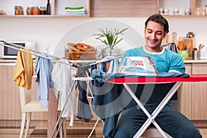 The young man husband doing clothing ironing at home