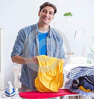 Young man husband doing clothing ironing at home